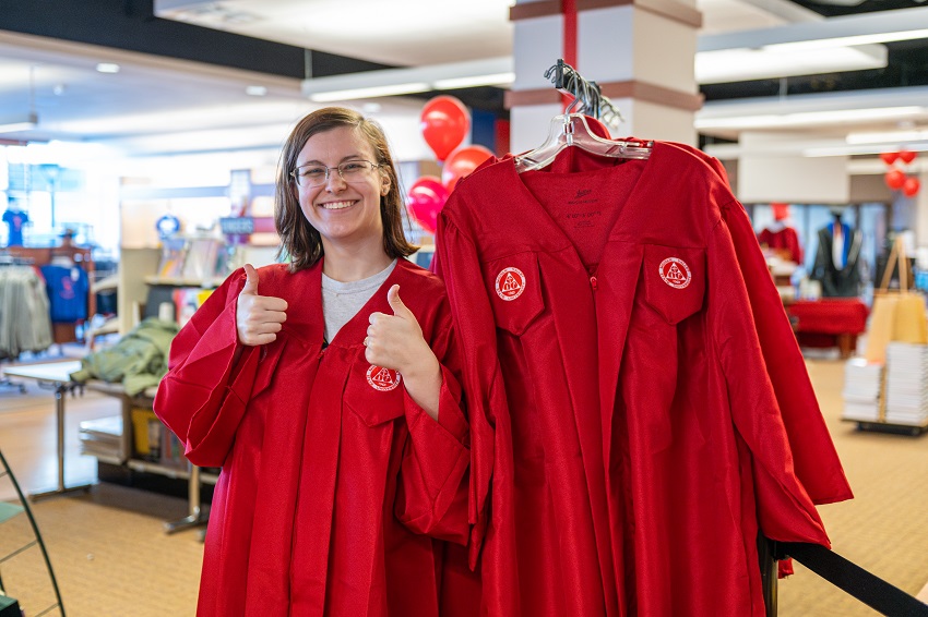 graduate in gown giving a thumbs up